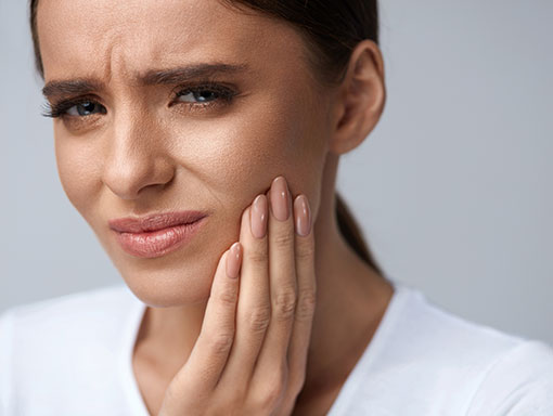 Woman-with-Jaw-Pain-TMJ | Smiles Unlimited set of dental teeth and toothbrush