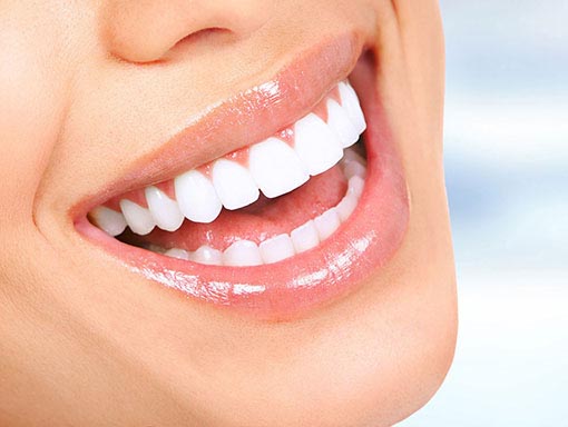 closeup of a girl's smile | Smiles Unlimited healthy teeth biting an apple